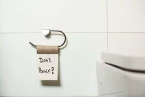 an empty roll of toilet paper hanging in the bathroom with the words "don't panic" showcasing the regular struggles of people with digestive issues