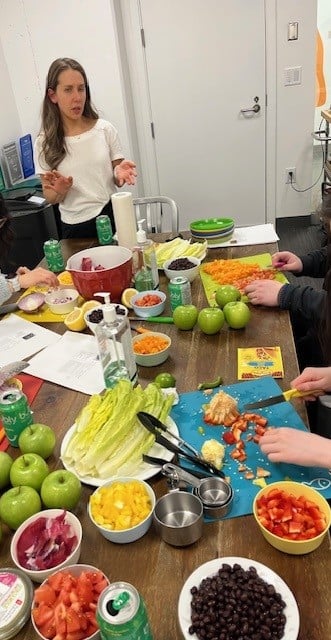registered dietitian teaching a cooking class for students at UBC. Students chopping up ingredients including lettuce, bell peppers, red onions