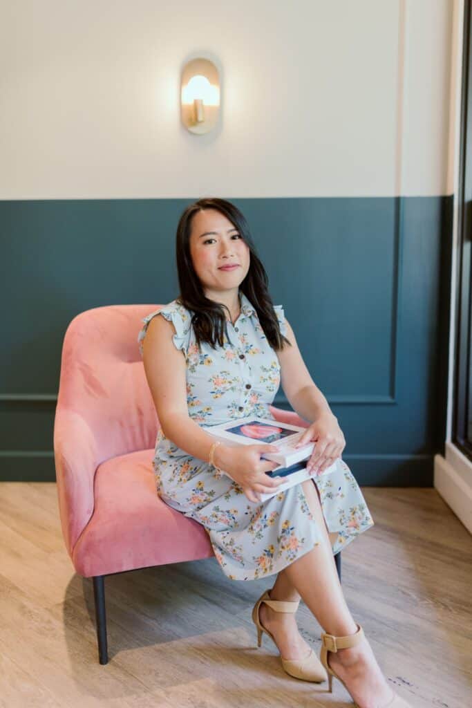 BC dietitian holding tack of nutrition books sitting on a pink chair