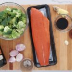 salmon, broccoli, garlic, ginger, soy sauce, salt and pepper, olive oil lay out on a chopping board