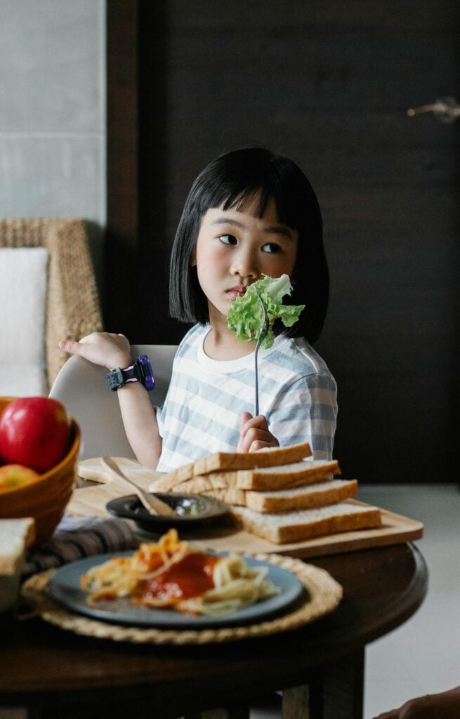 little girl black hair eating veggies