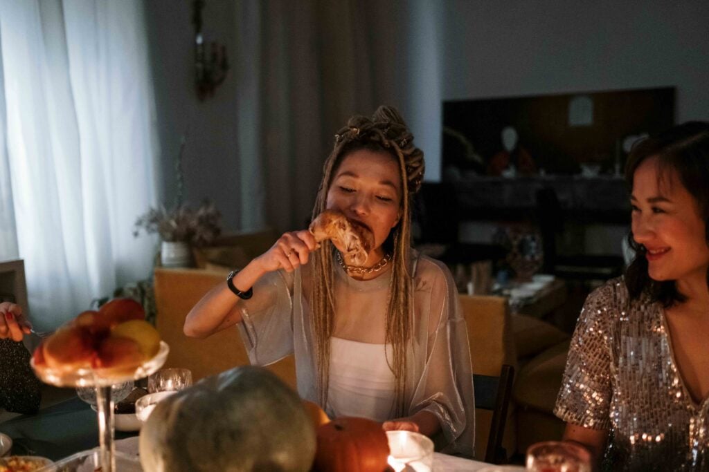 woman eating with friend in dimly lit room